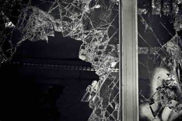 A shattered window glass in the dark depicting broken inner self, darak past memories, and misery.