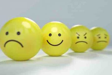Happy and sad emoticon balls with a happy emoticon ball in focus among the others depicting happiness even in sadness.