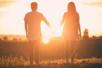 A couple holding hands and watching the sunlight depicting love, strength, and trust.