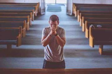 A man in the church kneeling and praying to God.