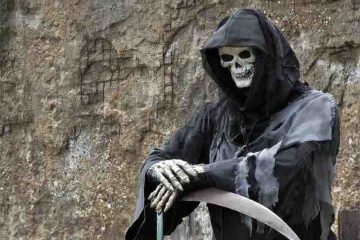 A skeleton with a black robe and clutching scythe depicting death.