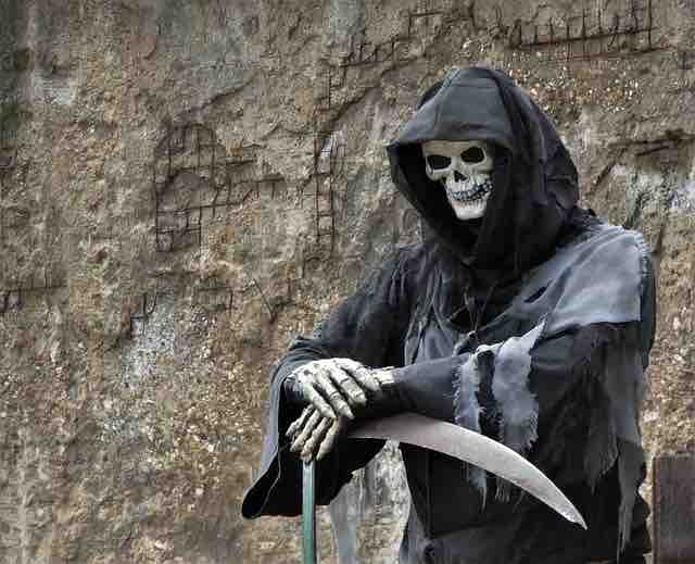 A skeleton with a black robe and clutching scythe depicting death.