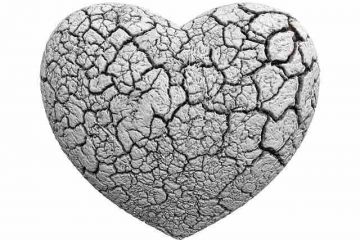 A white heart frozen and cracked but not completely broken depicting a troubled relationship on the verge of breakup.