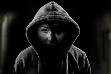 A woman with a hoodie and one side of the face in dark and other in the light depicting two sides of bipolar disorder.