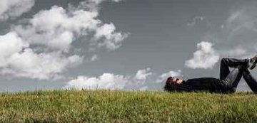 Man lying on the ground gazing at the sky depicting finding the meaning of life